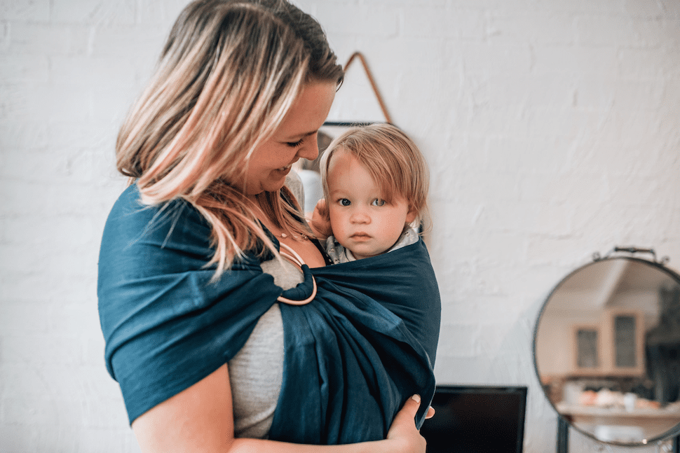 Mother wearing her child in a ring sling carrier