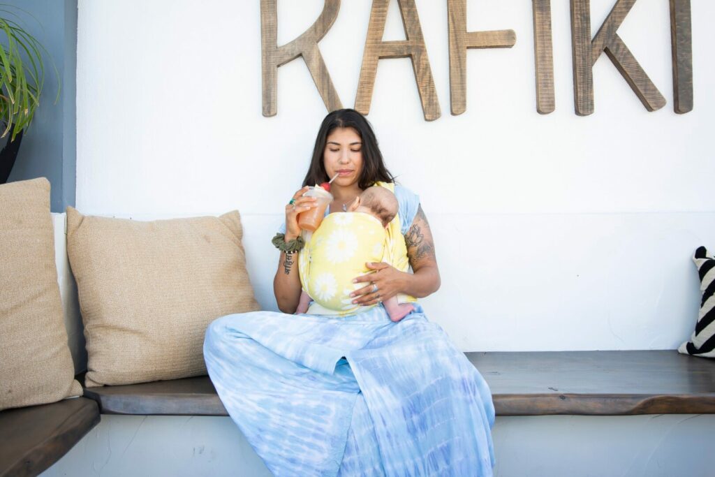 Woman wearing baby and sipping smoothie