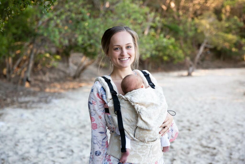 Lady at beach smiling and wearing her baby